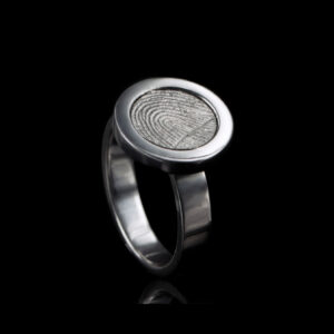 Ring met een ronde, verdiept liggende vingerafdruk, omlijst door een brede, gepolijste rand, gemaakt van zilver. Het ontwerp straalt elegantie en personalisatie uit.