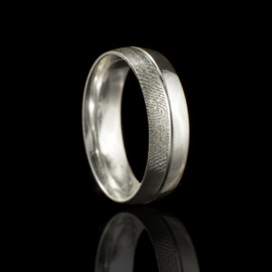 "Handgemaakte zilveren ring met subtiele vingerafdrukgravure aan de buitenkant, gecombineerd met een matte en gepolijste afwerking. Een elegant en gepersonaliseerd sieraad.